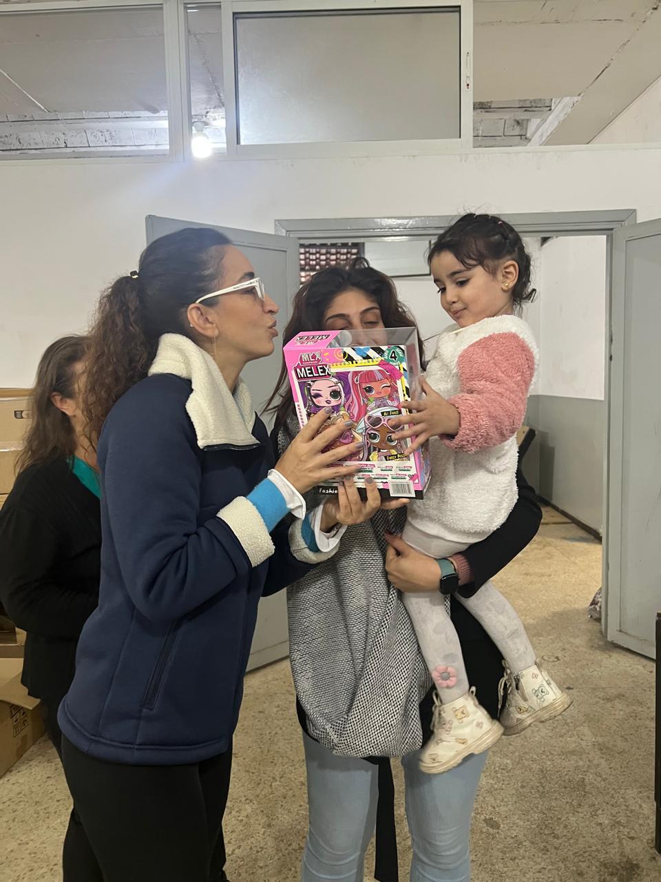 A volunteer sharing a gift with a young child and their family